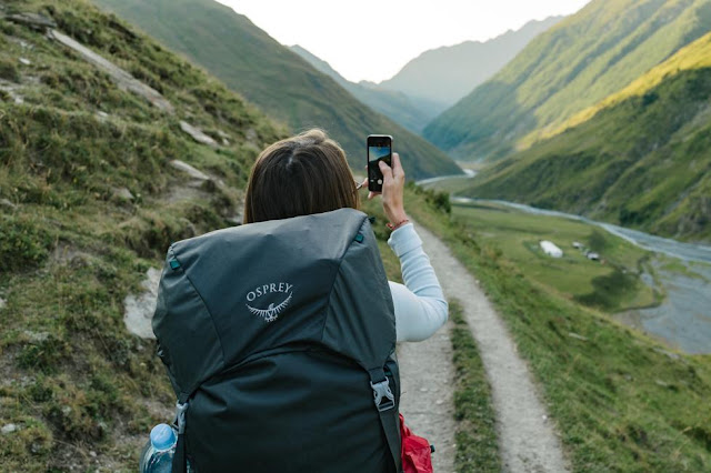 Woman with backpack taking a photo with her phone